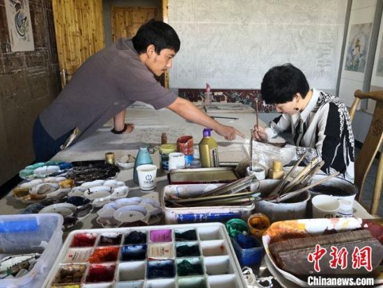 圖為2020年8月下旬，敦煌“80后”畫家張杰龍(左)在為云南麗江“學(xué)生”莫北講解敦煌壁畫的繪畫技巧?！●T志軍 攝