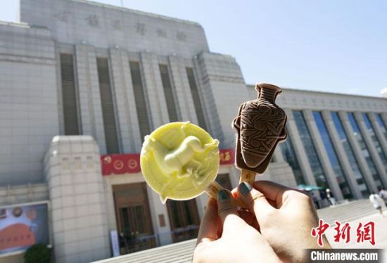 2021年7月30日，游客手拿“銅奔馬”“彩陶瓶”造型的雪糕，在甘肅省博物館前拍照打卡?！「哒?攝