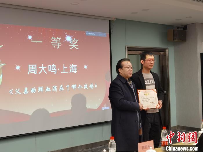 圖為作家、西北師范大學(xué)新聞與傳媒學(xué)院院長徐兆壽頒發(fā)一等獎證書，代領(lǐng)獎?wù)呱吓_領(lǐng)獎?！钅?攝