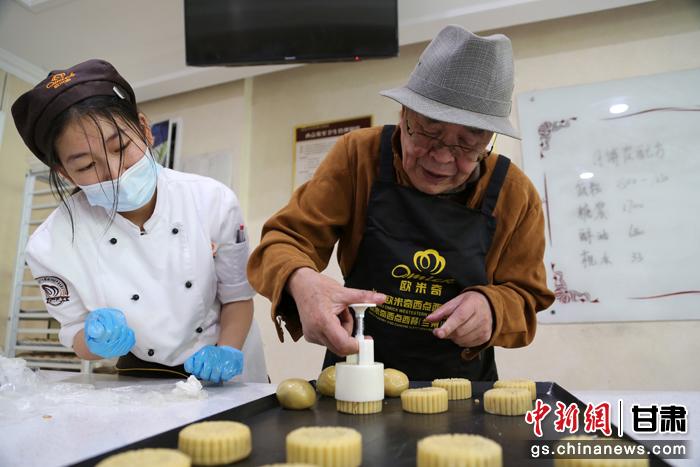 當日，受邀參加活動的臺胞臺屬代表、兩岸婚姻及子女、在甘臺商代表等歡聚一堂。圖為77歲的在甘臺胞潘天鑒制作月餅。九美旦增 攝