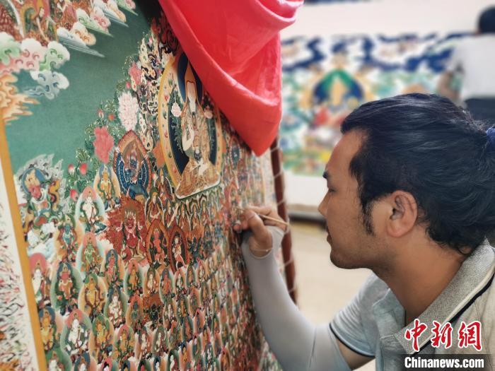 圖為更登才讓的徒弟繪畫唐卡?！?zhí)砀?攝