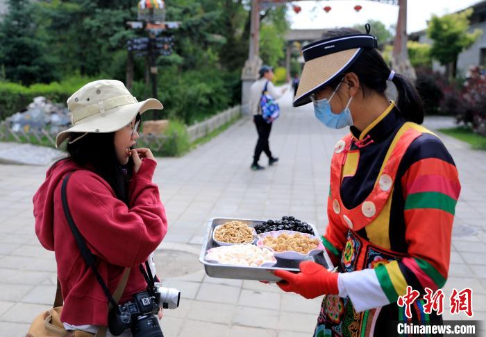 圖為身穿土族服飾的女性介紹當(dāng)?shù)靥厣〕?。　薛?攝