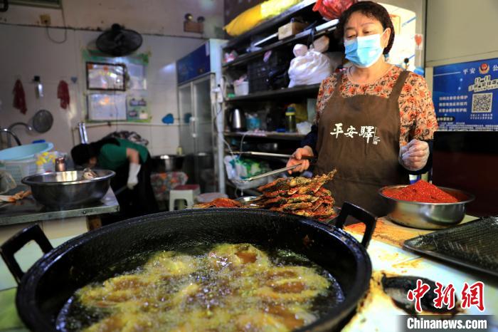 圖為平安驛·河湟民俗文化體驗(yàn)地內(nèi)的商戶炸干板魚?！⊙Φ?攝
