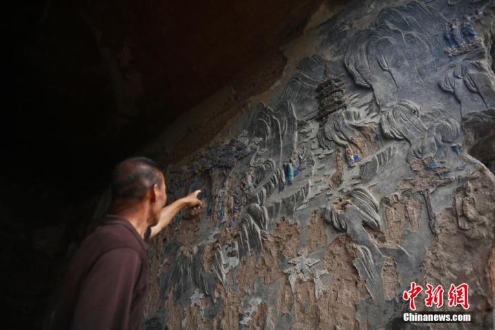 7月15日，甘肅省平?jīng)鍪袥艽h百里石窟長廊羅漢洞石窟內(nèi)，該窟文保員郭建平介紹窟內(nèi)石刻彩繪壁畫。郭建平家中三代人曾自發(fā)保護(hù)羅漢洞石窟。羅漢洞石窟遺存40余個(gè)窟龕，以北魏至清代風(fēng)格為主。中新社記者 李亞龍 攝