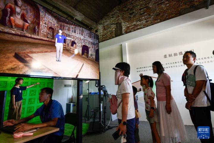 7月22日，游客體驗(yàn)“尋境敦煌——數(shù)字敦煌沉浸展”后，在虛擬演播廳拍攝一段真人與洞窟虛擬場(chǎng)景交互的視頻。新華社記者 郎兵兵 攝</p>
<p>
