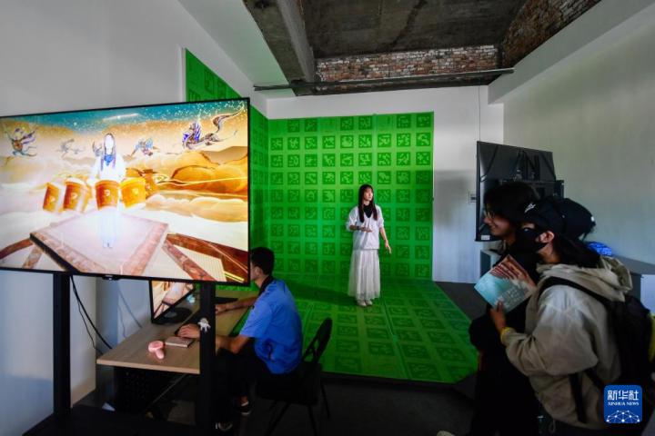 7月22日，游客體驗(yàn)“尋境敦煌——數(shù)字敦煌沉浸展”后，在虛擬演播廳拍攝一段真人與洞窟虛擬場(chǎng)景交互的視頻。新華社記者 郎兵兵 攝</p>
<p>